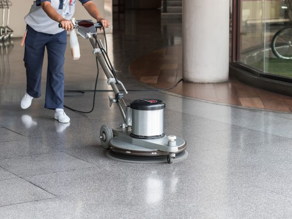 Woman worker cleaning the floor with polishing machine